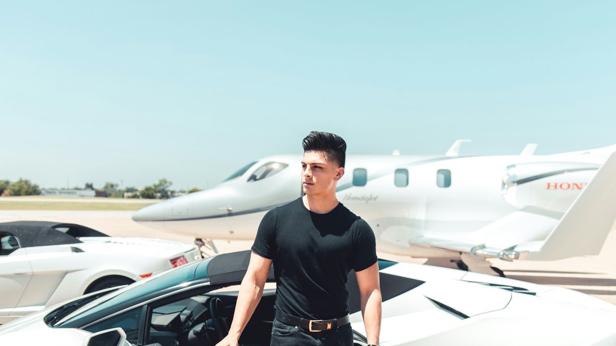 man standing in front of expensive cars and private jet
