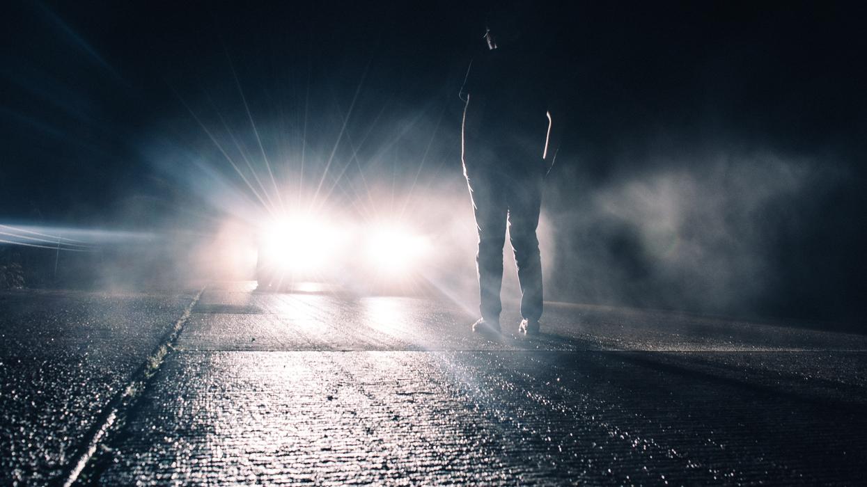 man standing in front of lighted car