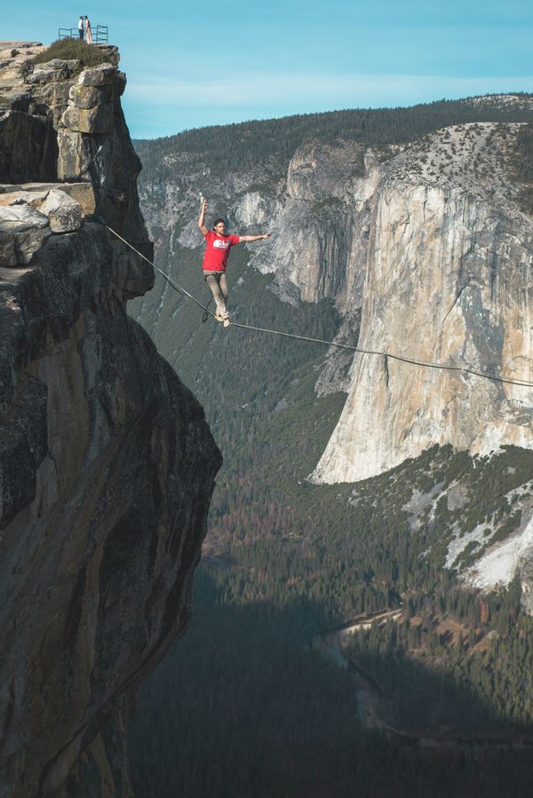 Man walking a tight rope between two cliffs