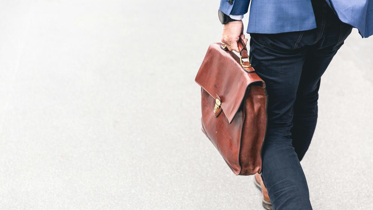 Man walking out of office with a work suitcase