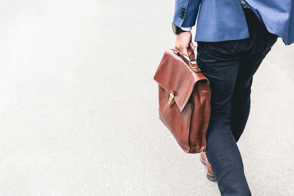 Man walking out of office with a work suitcase