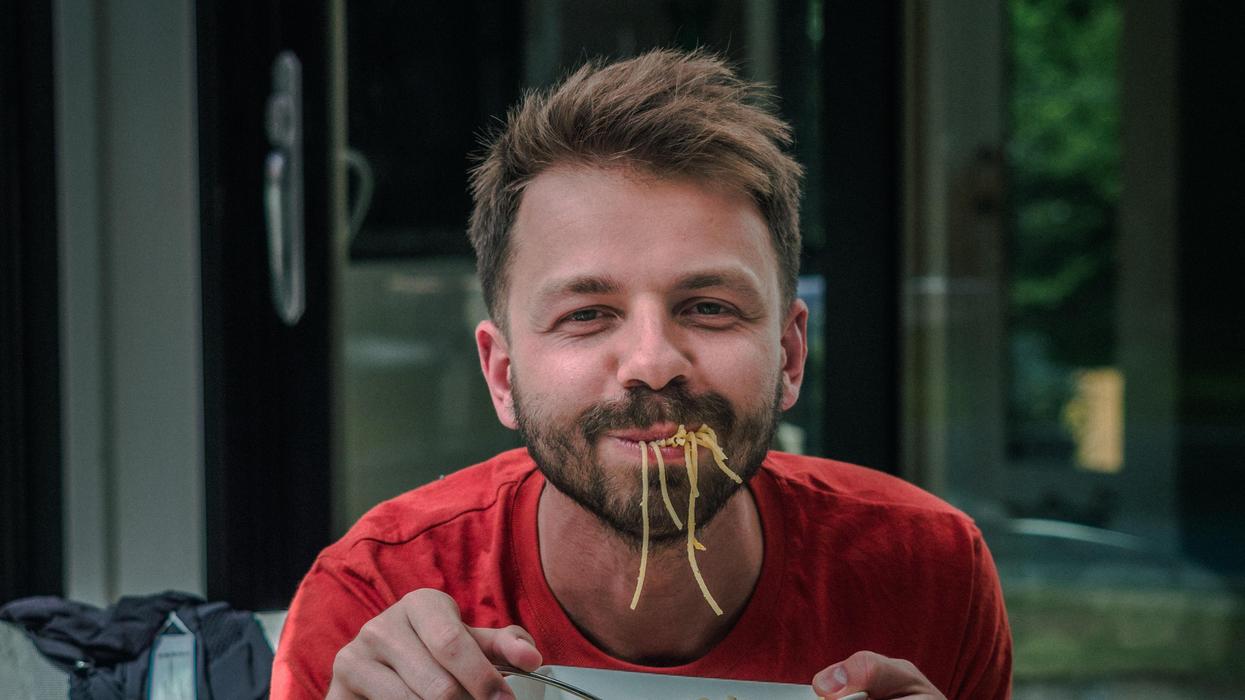 Man with noodles dangling from his mouth