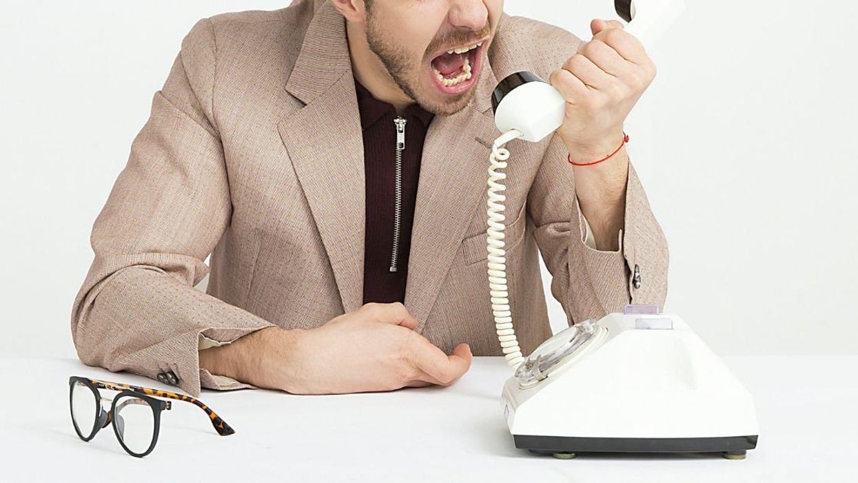 Man yelling angrily into a rotary-dial telephone