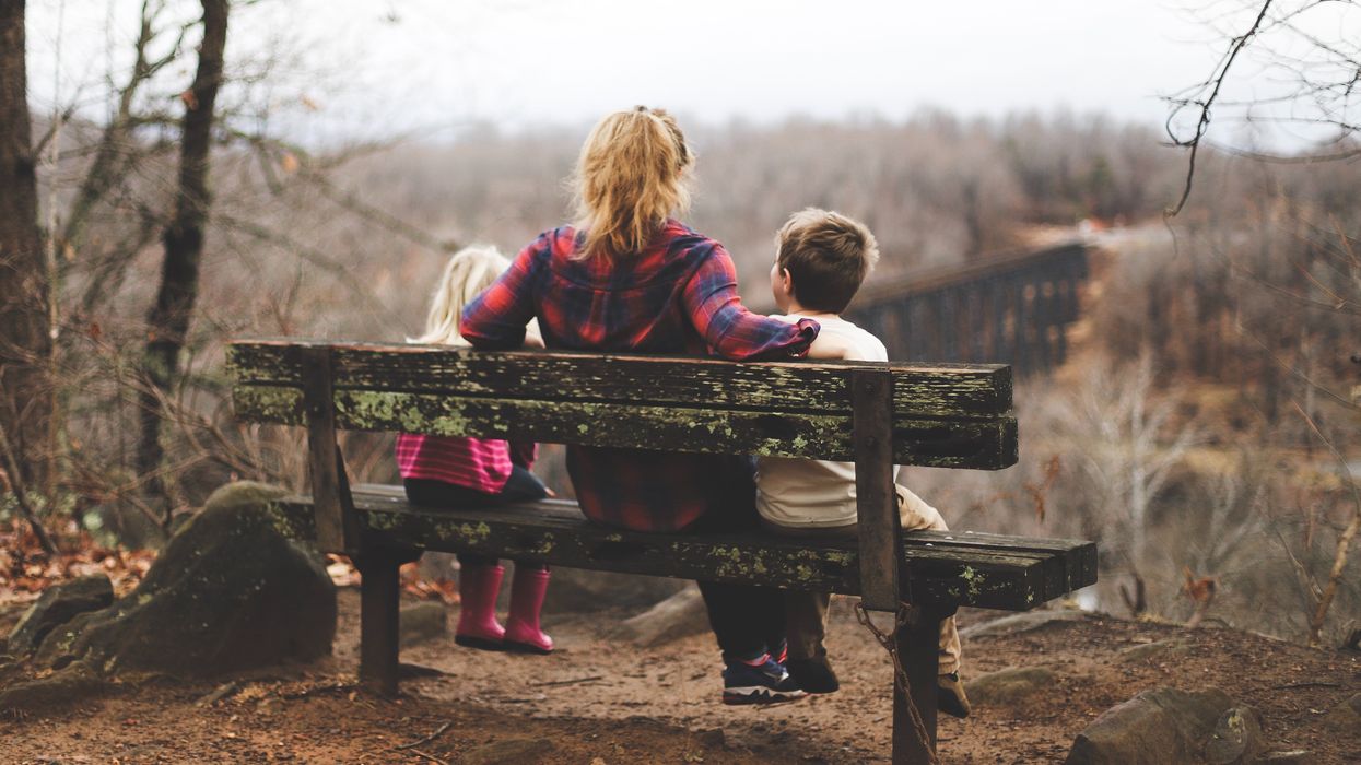 Mother sitting on bench with two children