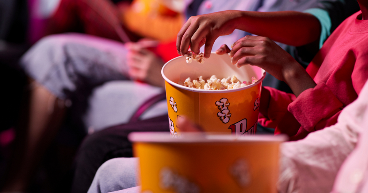 movie theater seats with patrons with buckets of popcorn and no visible faces