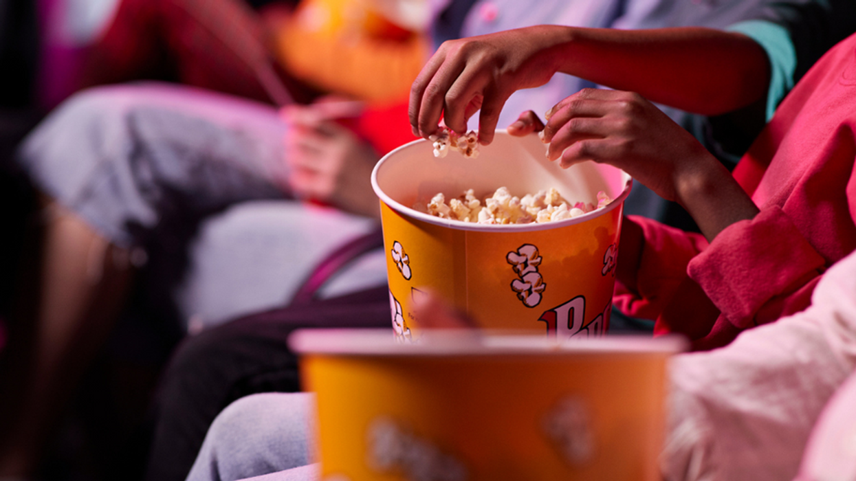 movie theater seats with patrons with buckets of popcorn and no visible faces