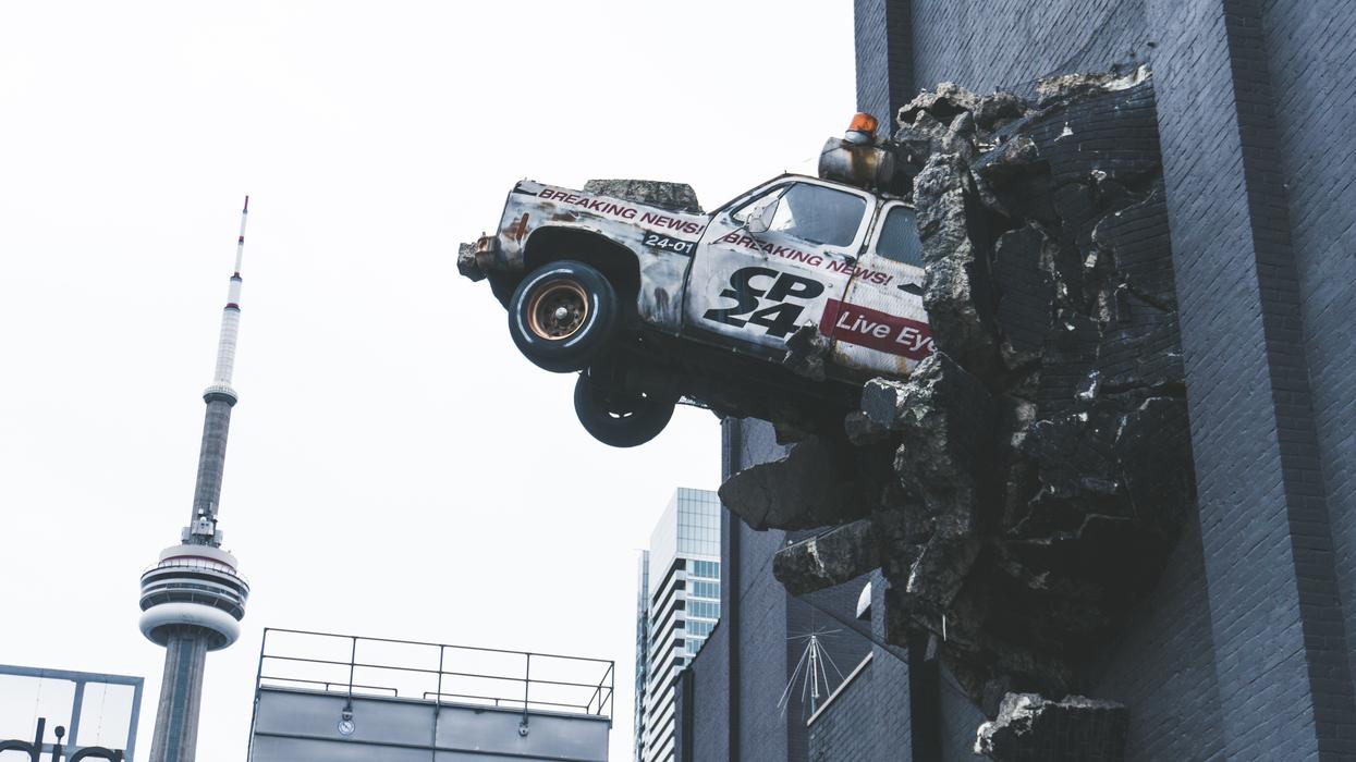 Newsvan breaking through the side of a brick building