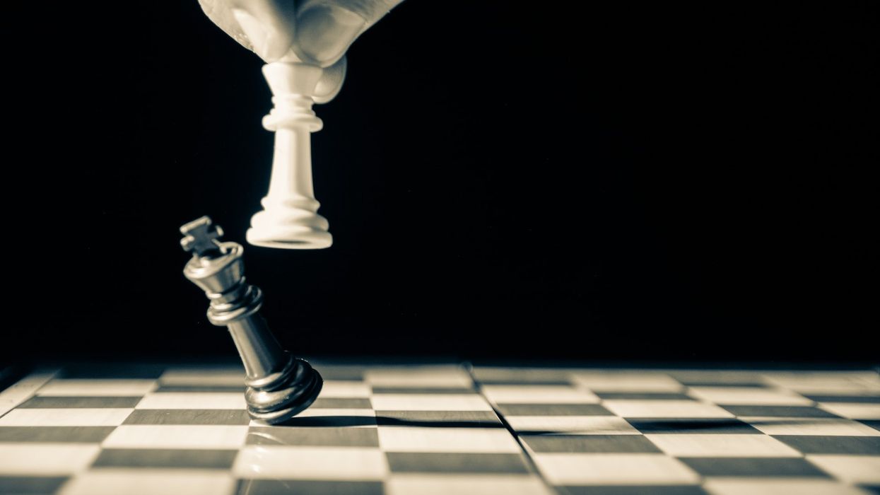 On a black and white chessboard a White King topples a Black King