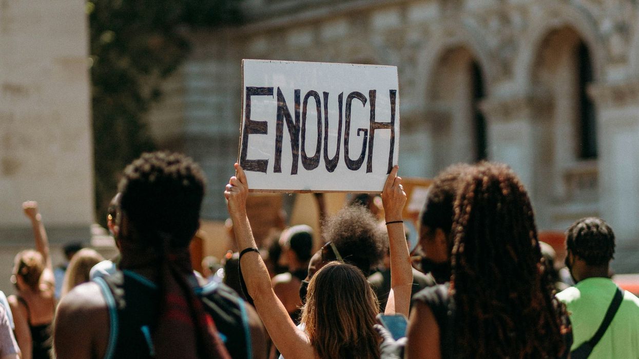 People protesting, one protestor holding a sign that reads, 'Enough'