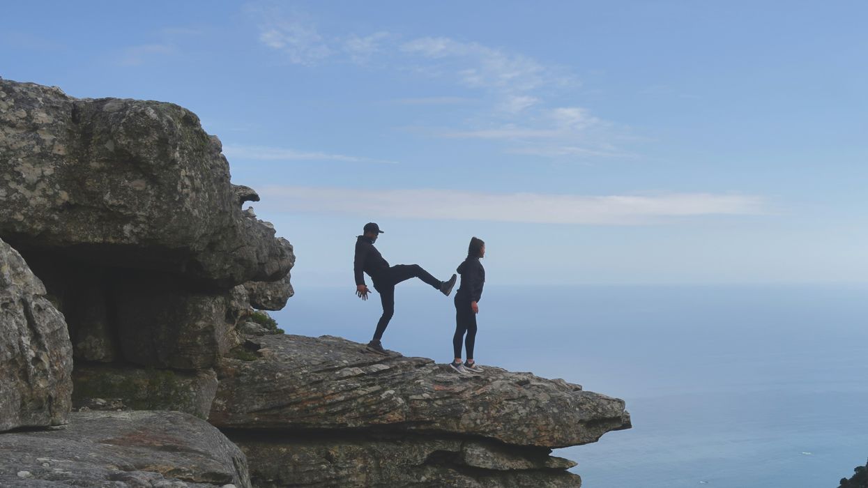 Person about to kick someone off a cliff