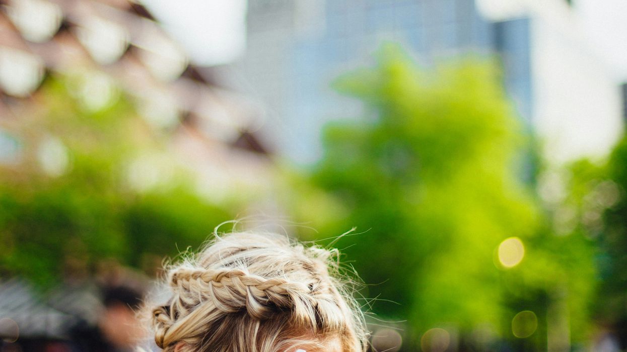 person covering face with hands outdoors