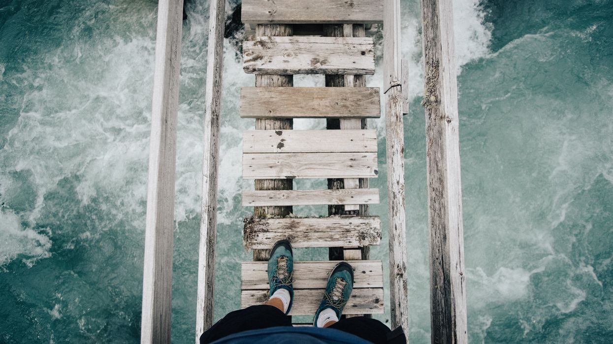 Person crossing wooden bridge above glacial river