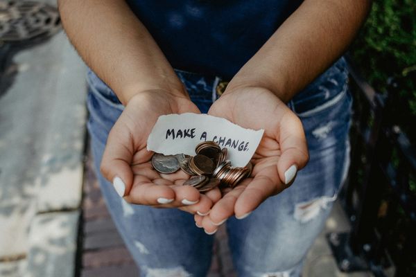 person cupping both hands with 'make a change' note and coins