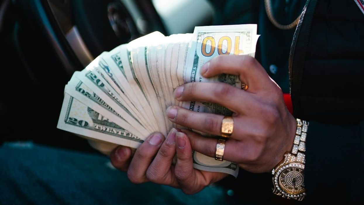 Person fanning out a wad of $100 bills