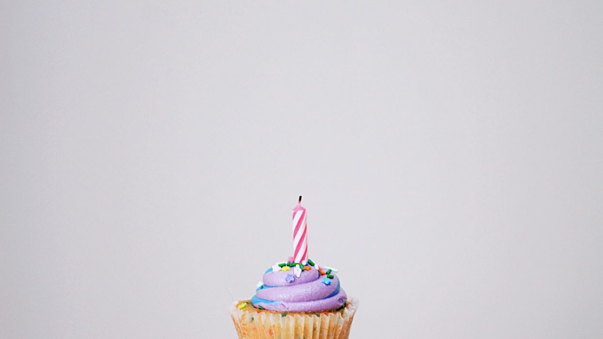 Person holding a cupcake with candle