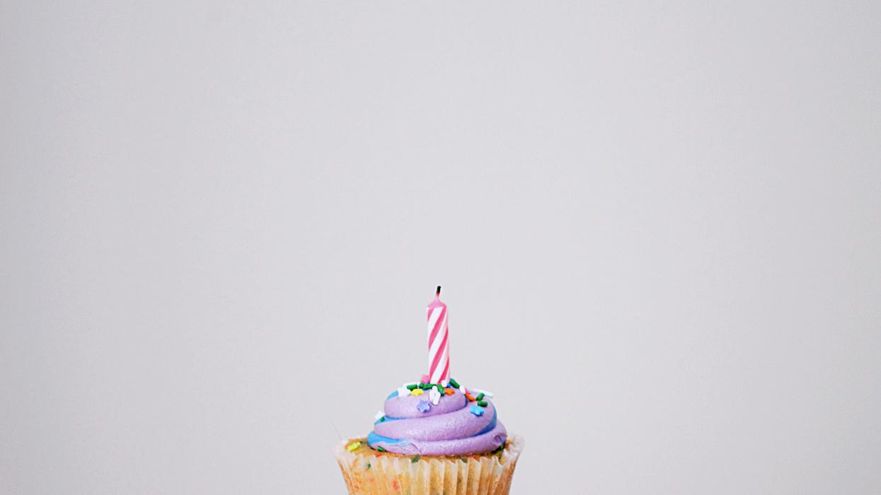 Person holding a cupcake with candle