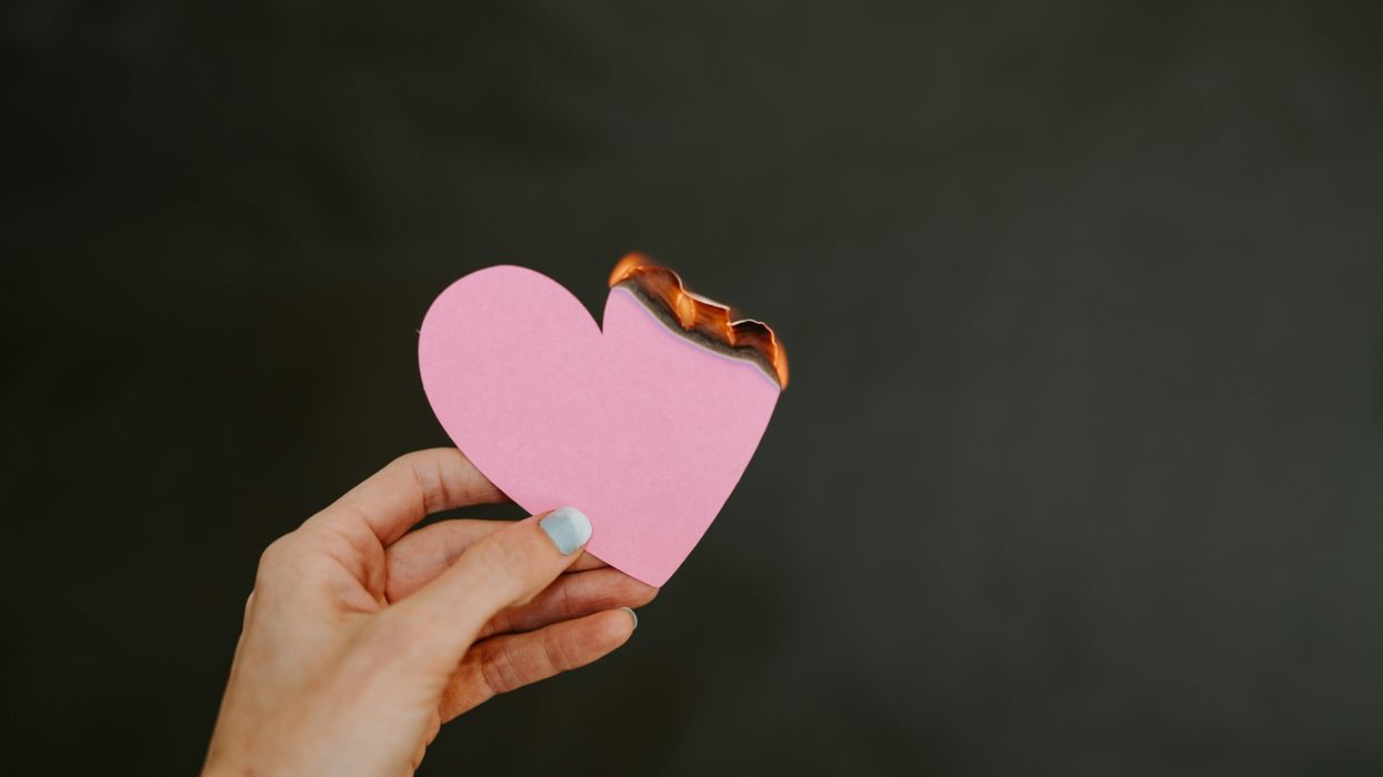 Person holding a paper heart that's been lit on fire