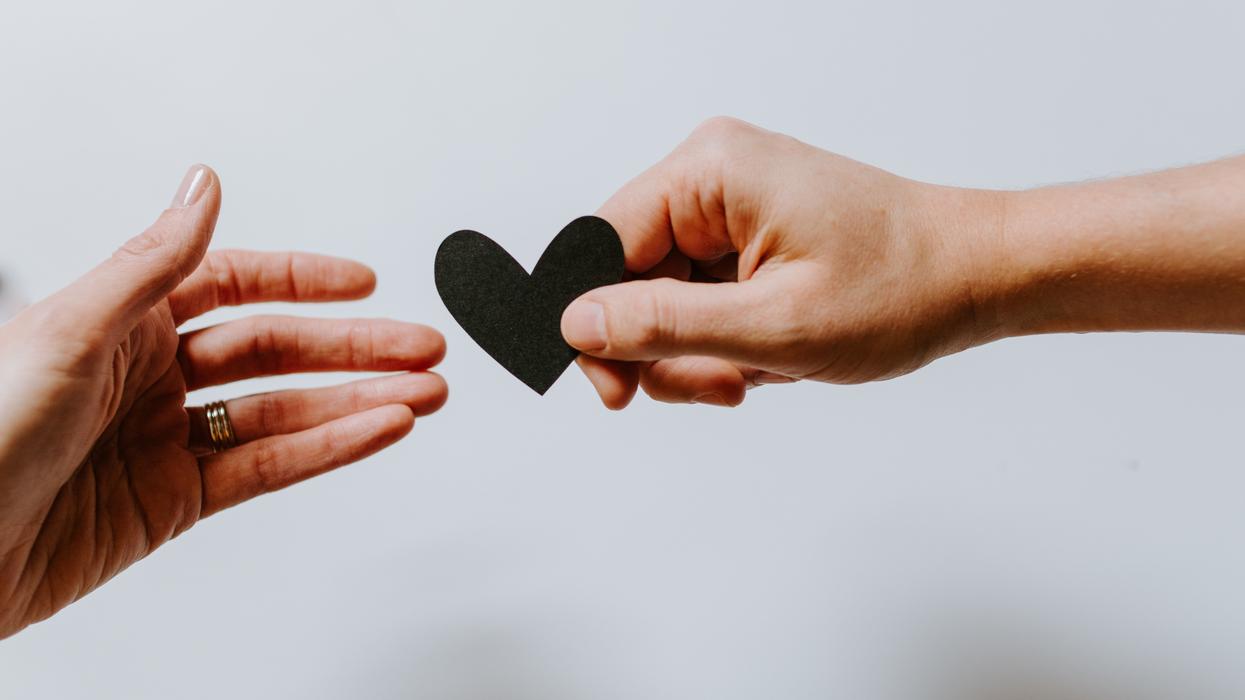 Person holding out paper heart to another person