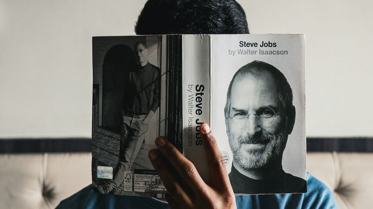 Person holding up a copy of 'Steve Jobs' by Walter Isaacson in front of their face