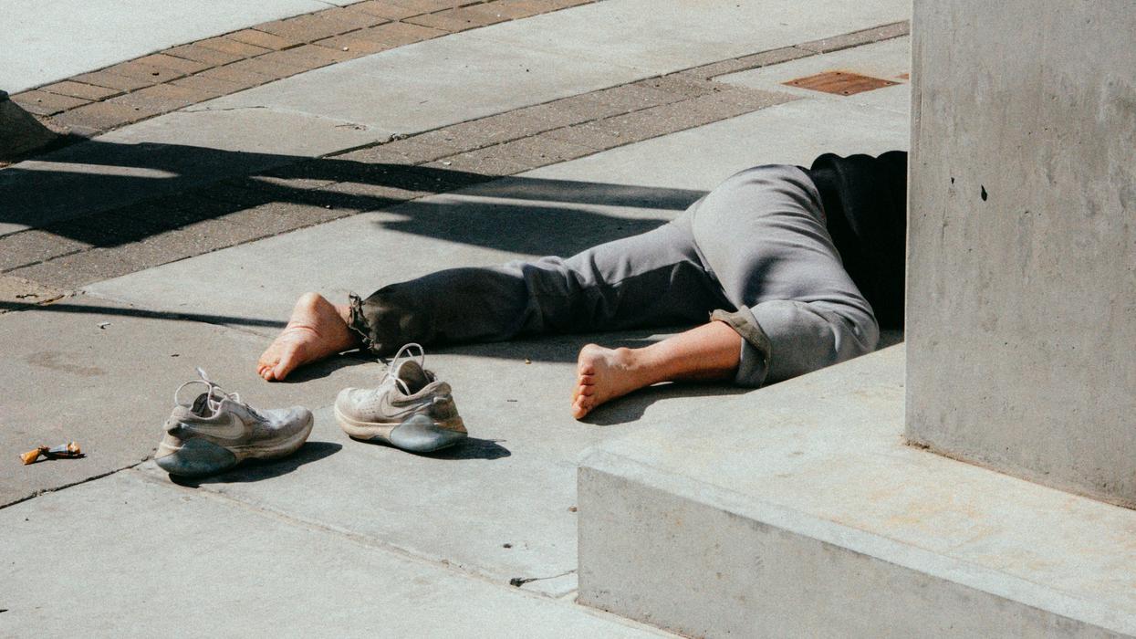 person in gray pants and gray shoes sitting on concrete bench