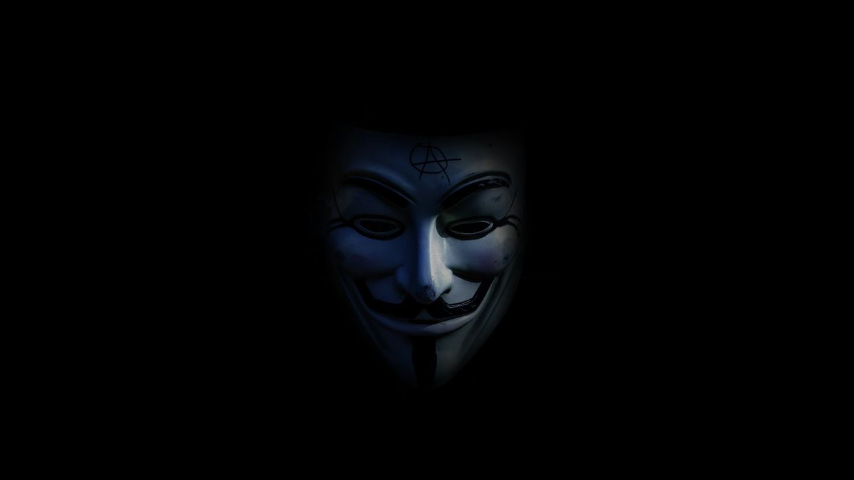 person in Guy Fawkes mask in low light