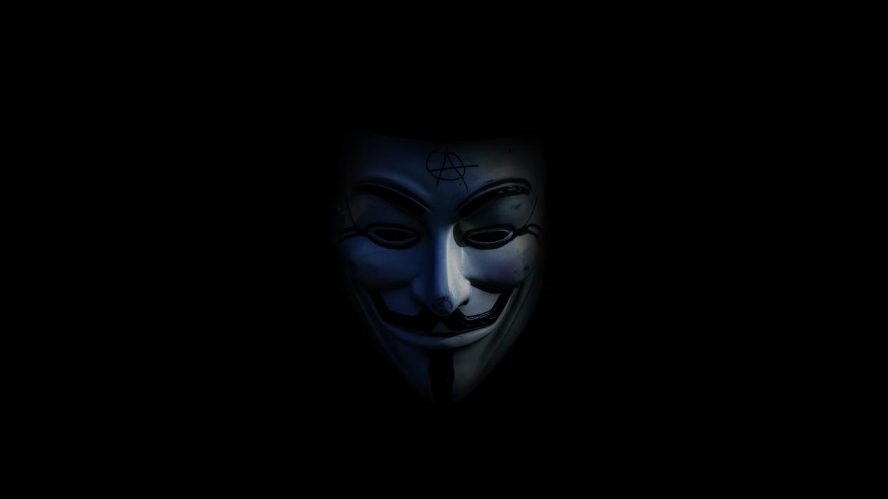 person in Guy Fawkes mask in low light