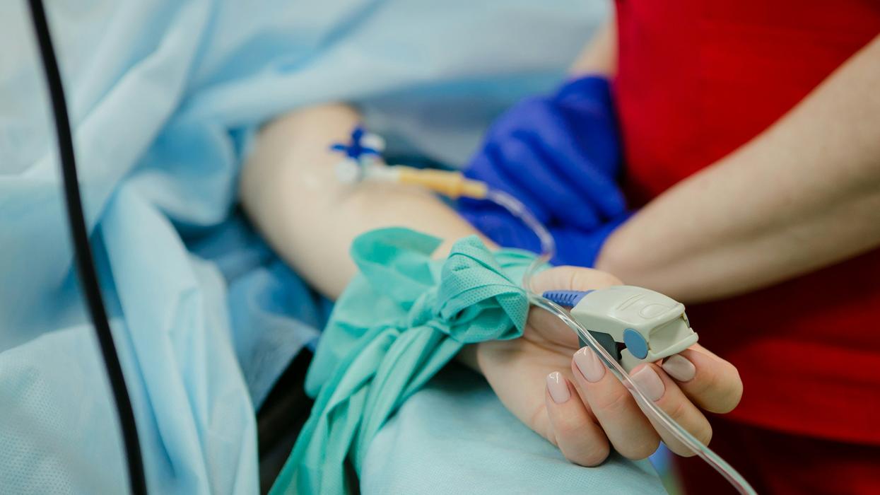 person lying on gurney with IV and pulse-ox monitor