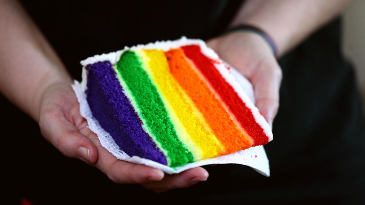 Person offering a slice of Pride cake
