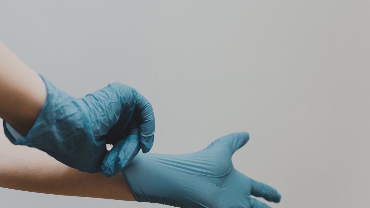 Person pulling on blue latex gloves