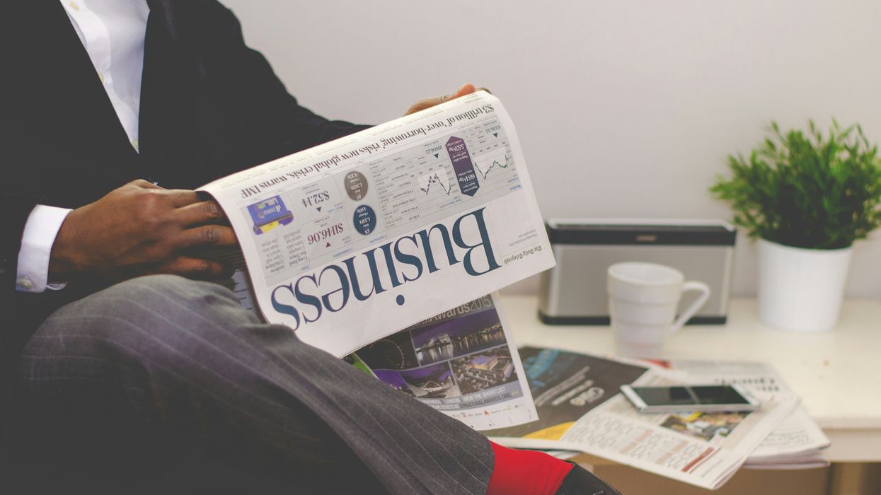 person sitting near table holding business newspaper