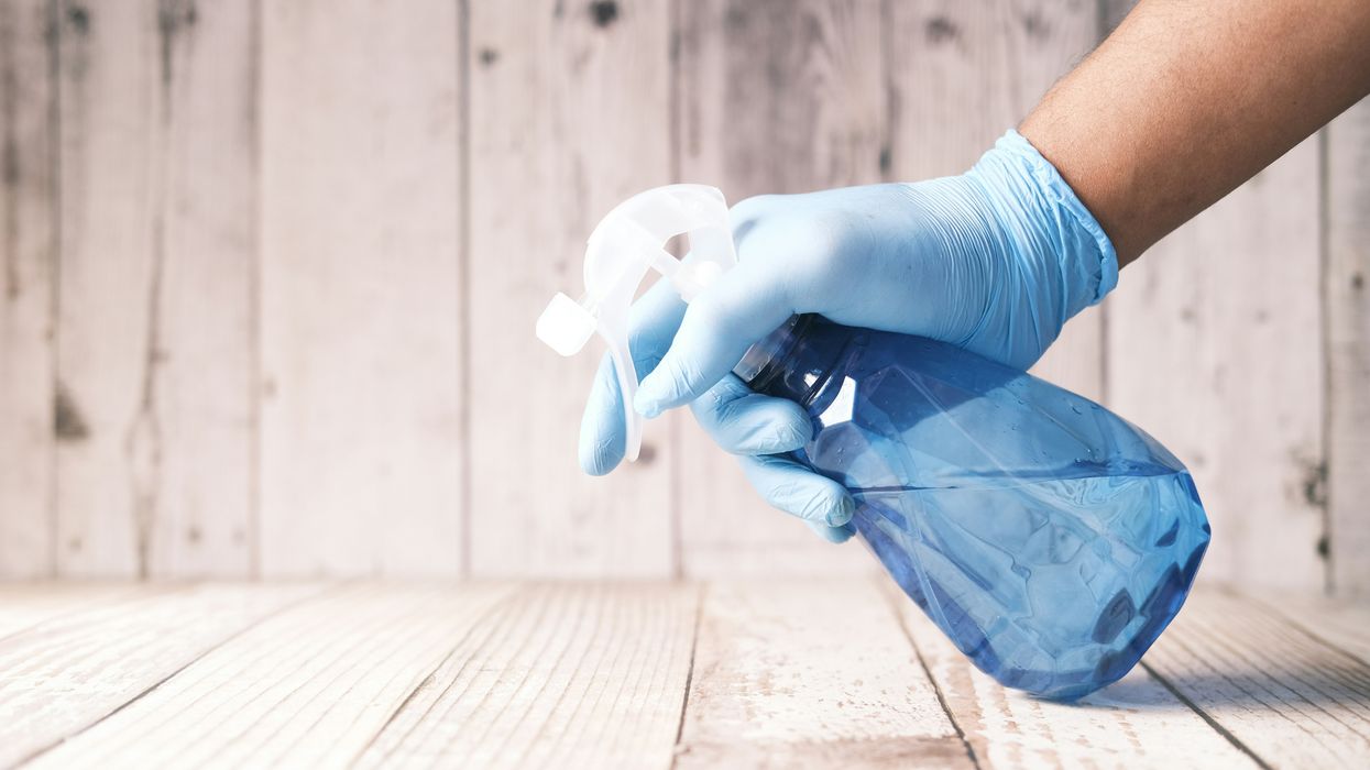 Person spraying cleaning solution on wooden surface