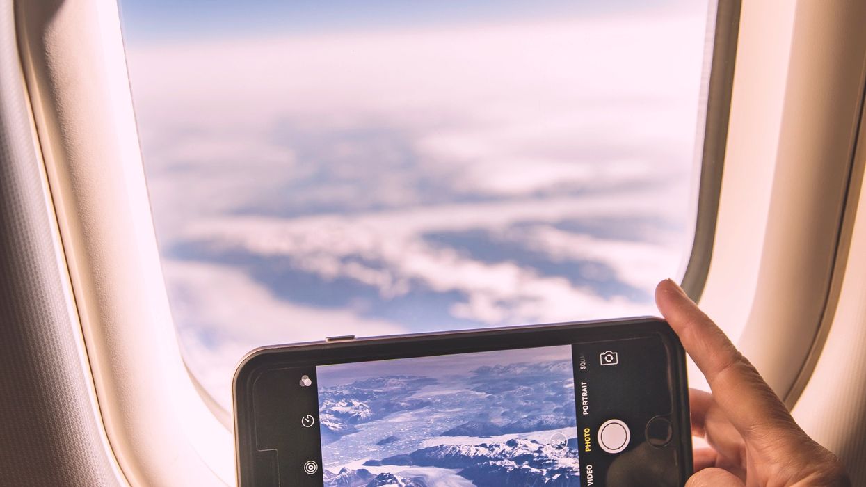 Person taking picture of the clouds from their seat on flight