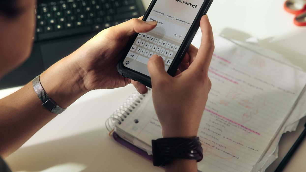 Person using a smartphone over a notebook