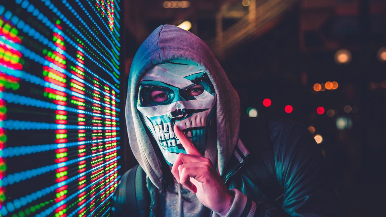 Person wearing a skull mask and shushing the camera