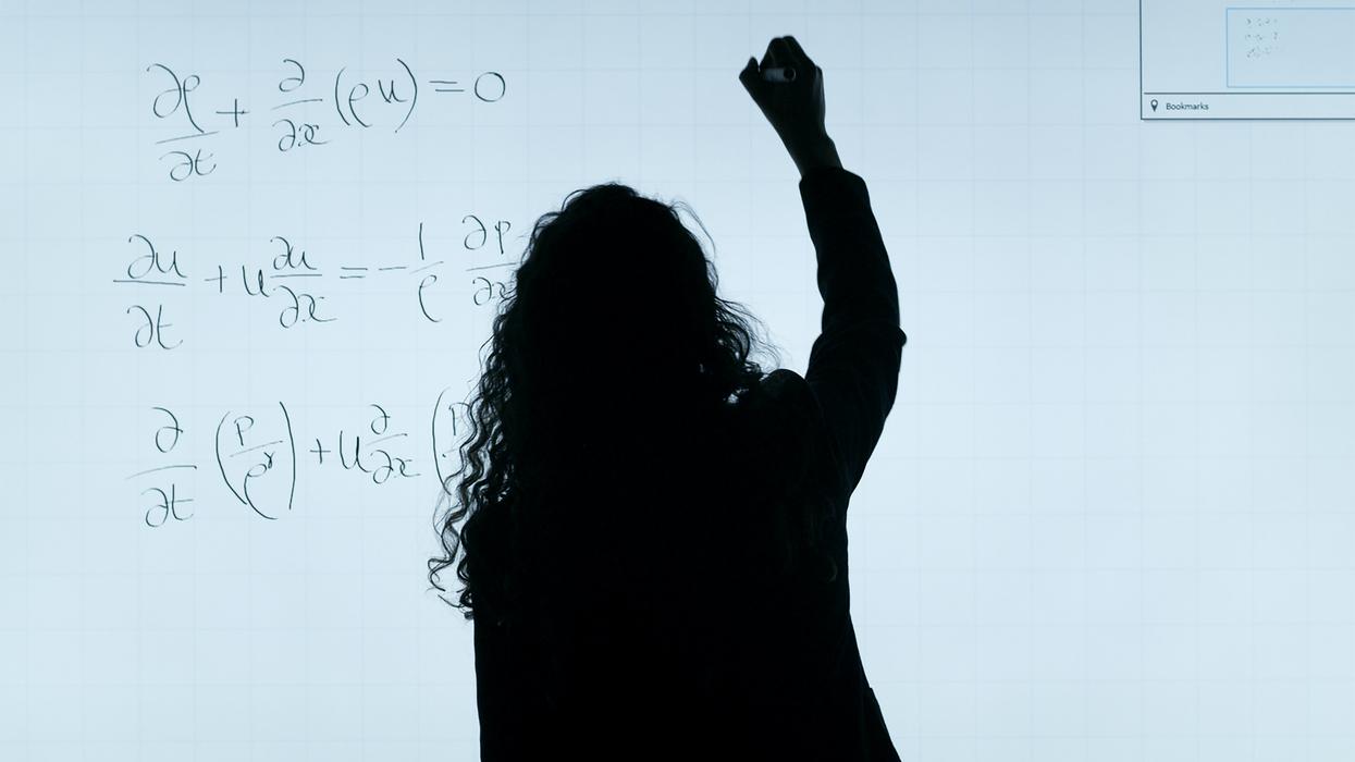Person writing a complicated formula on a white board