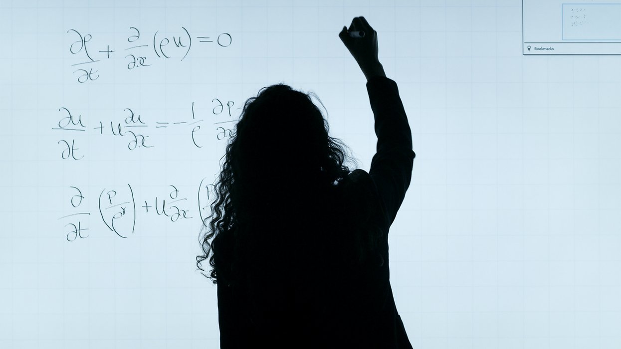 Person writing a complicated formula on a white board