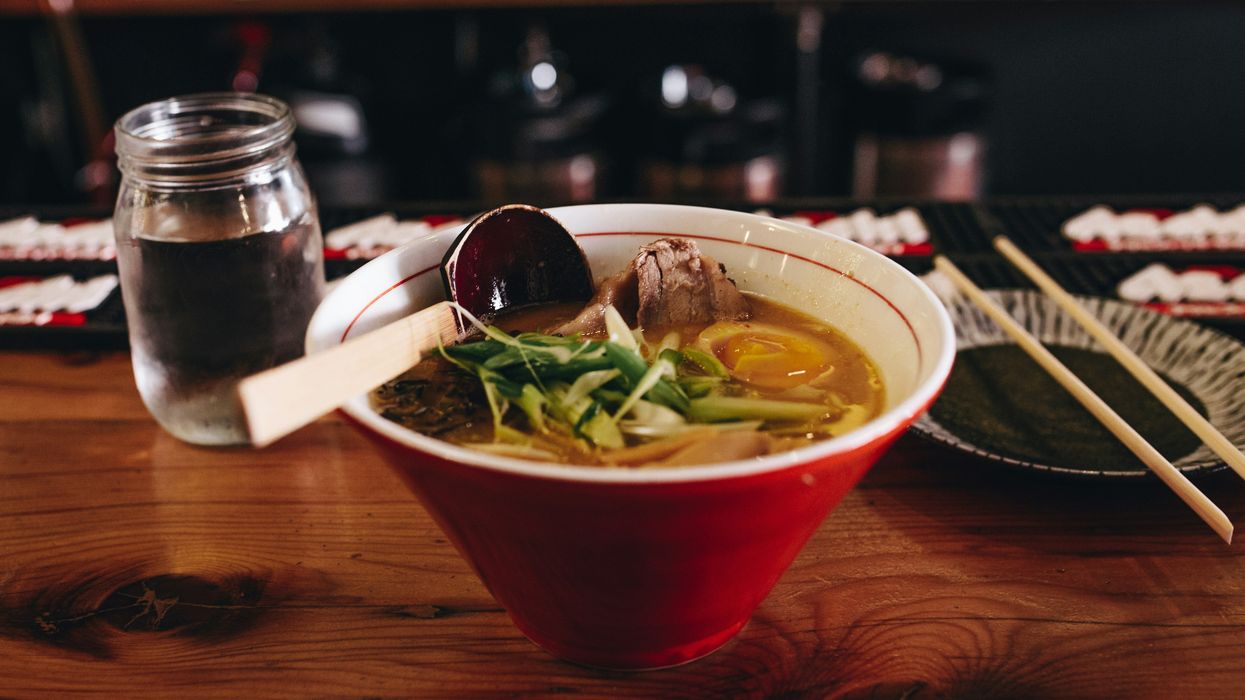pho with vegetables beside chopsticks and glass of water