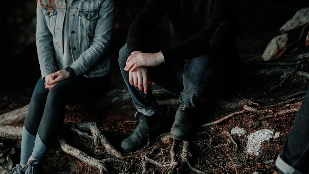 Photo of a couple sitting solemnly in the woods