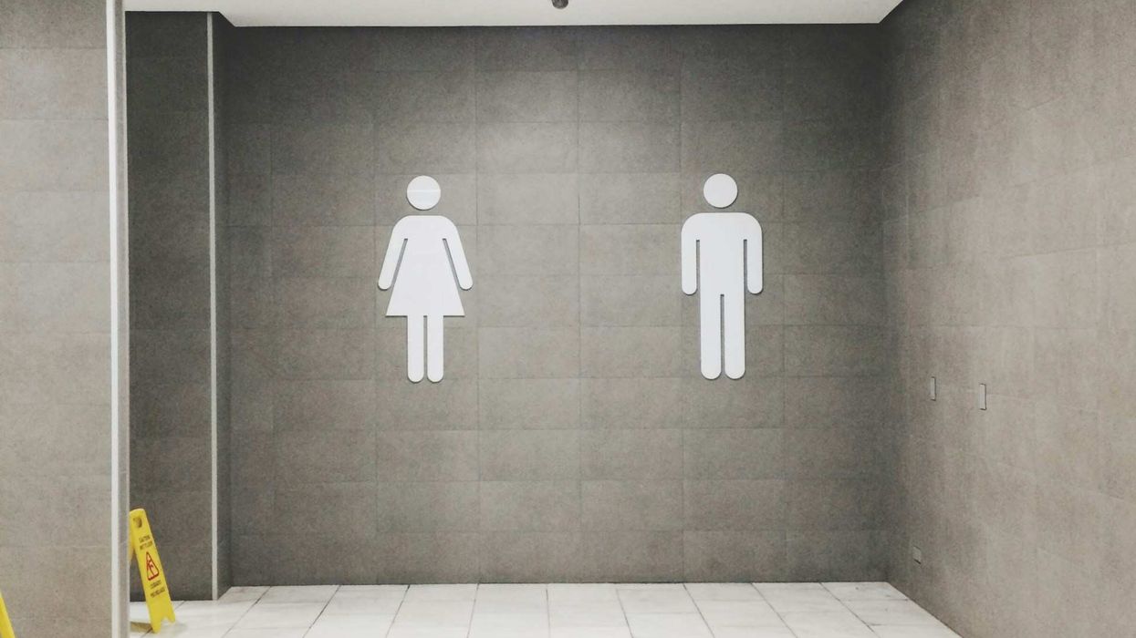 Photo of a grey walled bathroom with the man and woman symbols on the wall.