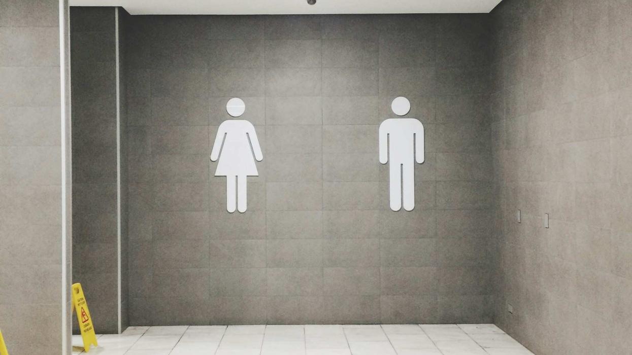 Photo of a grey walled bathroom with the man and woman symbols on the wall.