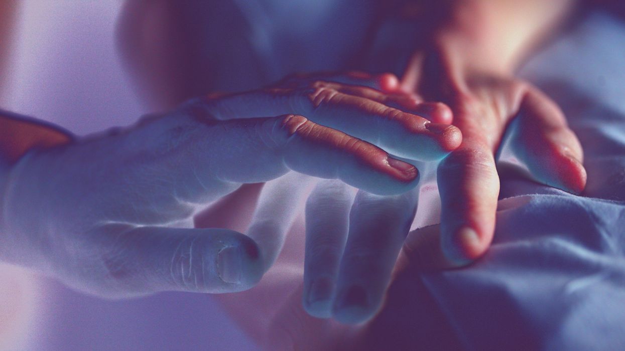 Photo of one hand laying on another. The photo is half superimposed with blue light.