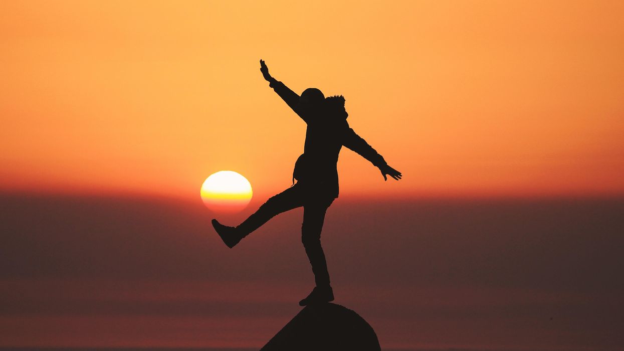 photo of silhouette photo of man standing on rock