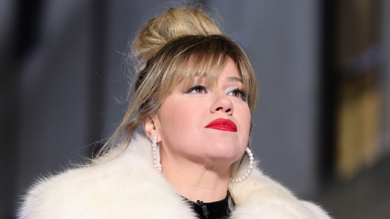 Photo of singer Kelly Clarkson. She is wearing a fluffy white jacket and large pearl hoop earrings.