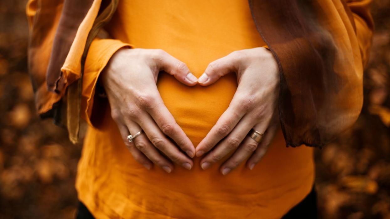 Pregnant woman forming a heart with hands over belly