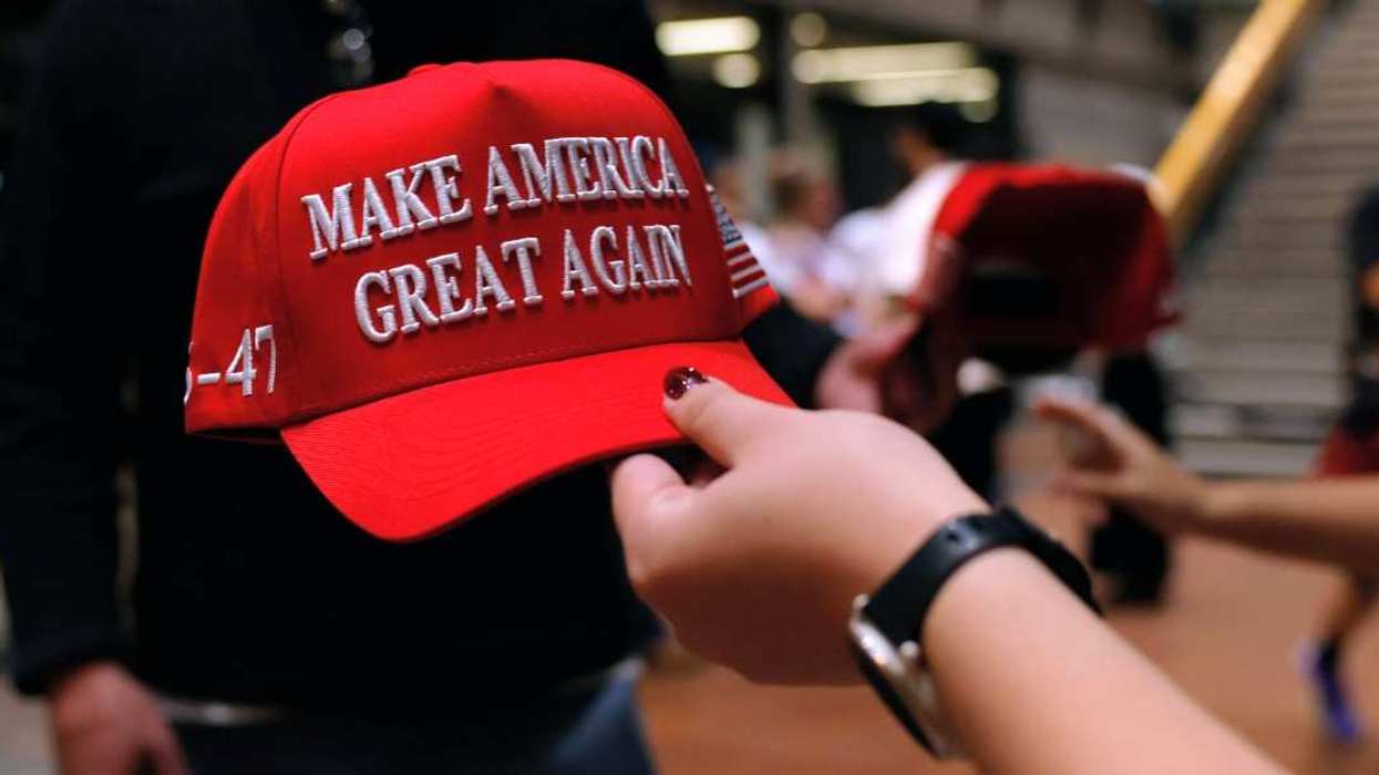 Red cap with "Make America Great Again" text held by a hand with a black watch.