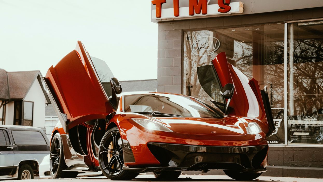 red ferrari 458 italia parked beside white building