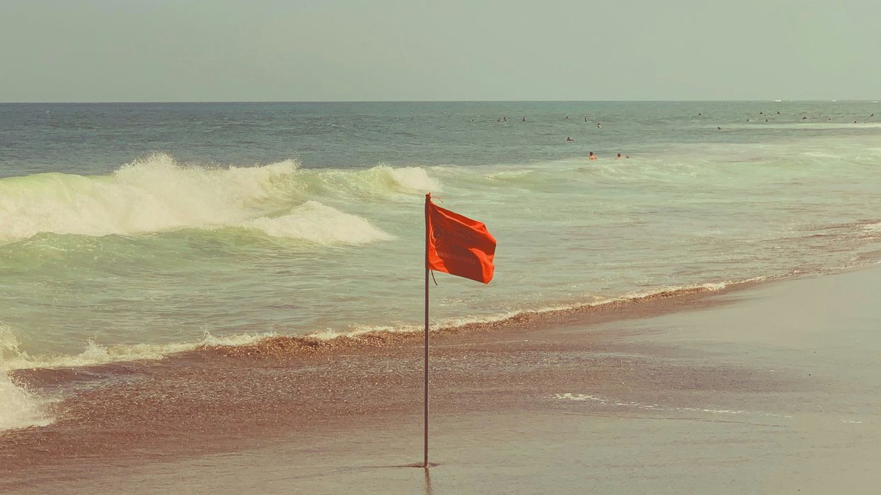 red flag with pole on seashore