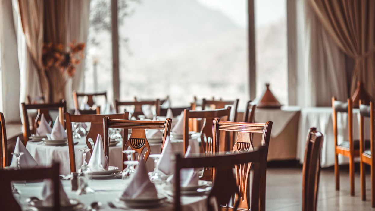 Restaurant dining room with brown wood chairs and white table cloths and cloth napkins