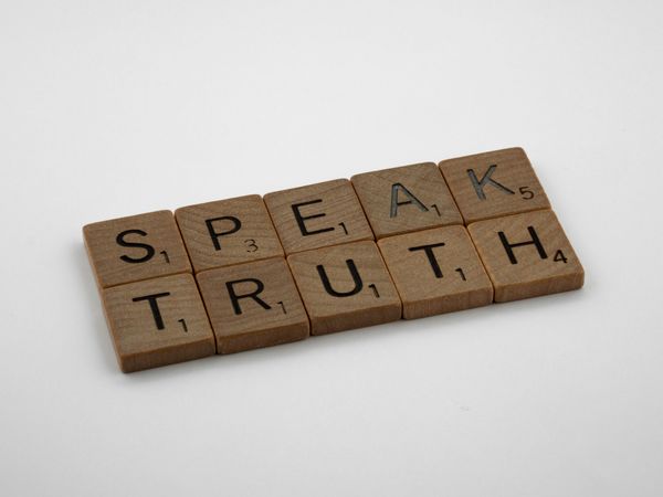 Scrabble tiles spelling "speak, truth".