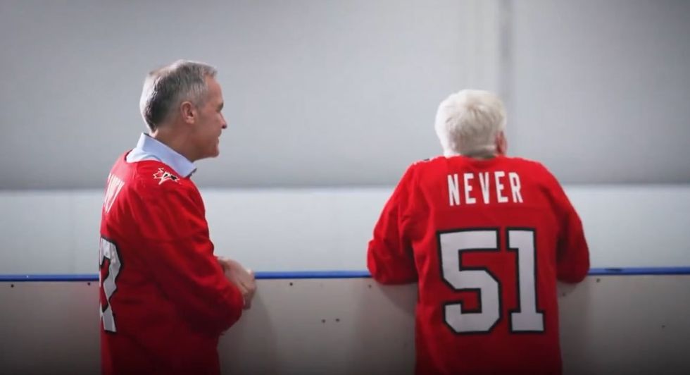 Screenshot of Mark Carney and Mike Myers, who wears "Never 51" jersey